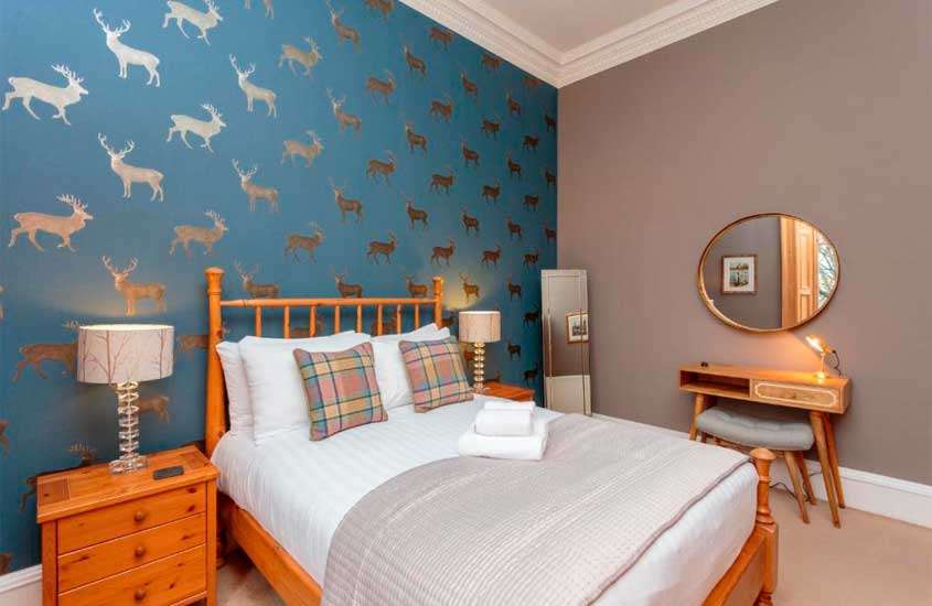 Quarto de hotel onde ficar em Edimburgo com cama de casal, luminárias, espelhos, papel de parede decorativo e escrivaninha com banco