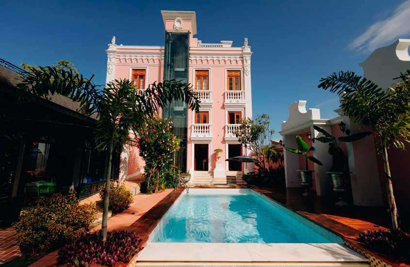 Em dia de sol, plantas e árvores ao redor de piscina externa de hotel em Florianópolis