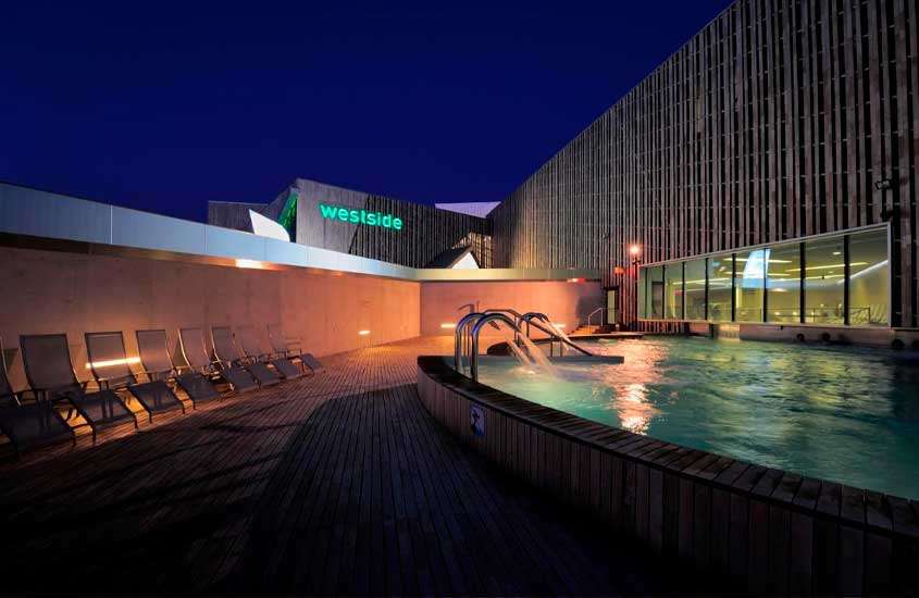 Durante a noite, espreguiçadeiras ao redor de piscina externa em cobertura de hotel em Berna