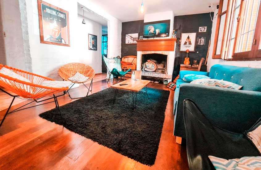 Sala de estar com lareira, cadeiras, tapete, mesa, quadros e janela de madeira em um dos melhores hostels em Montevideu