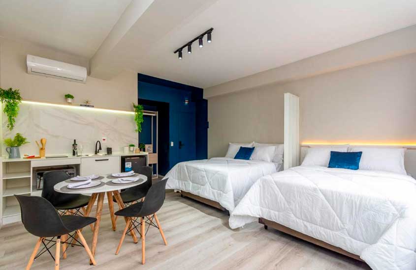 Quarto de hotel pet friendly SP com 2 camas de casal, mesa posta com cadeiras, mini-cozinha e ar-condicionado