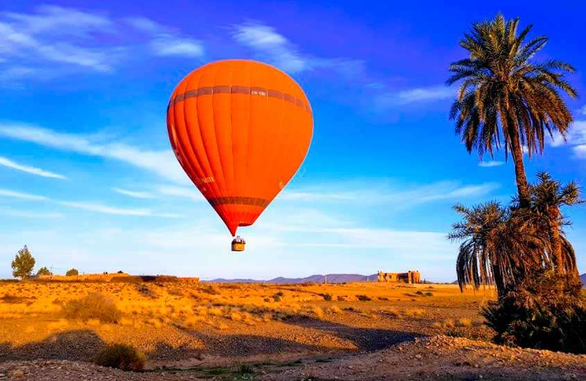 Em dia de sol, balão de ar quente laranja com árvores ao redor no céu de Marrakech Marrocos