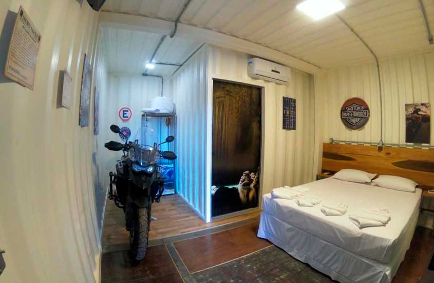 Quarto de hotel em bonito com cama de casal, moto, ar-condicionado, tapetes e quadros decorativos