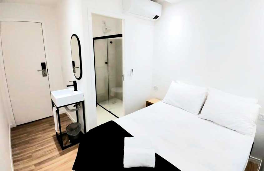 Quarto de hostel em sp com cama de casal, ar condicionado, espelho, pia e banheiro ao lado