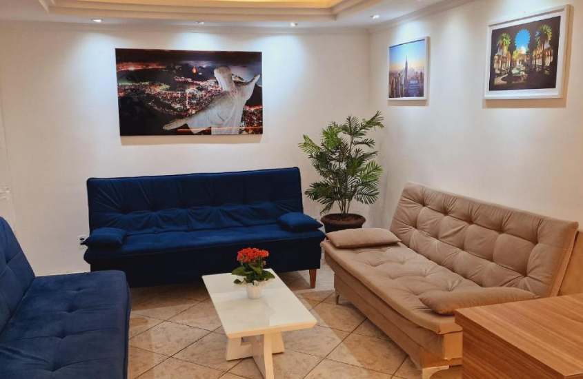 Sala de estar com sofás, mesa, plantas e quadros decorativos