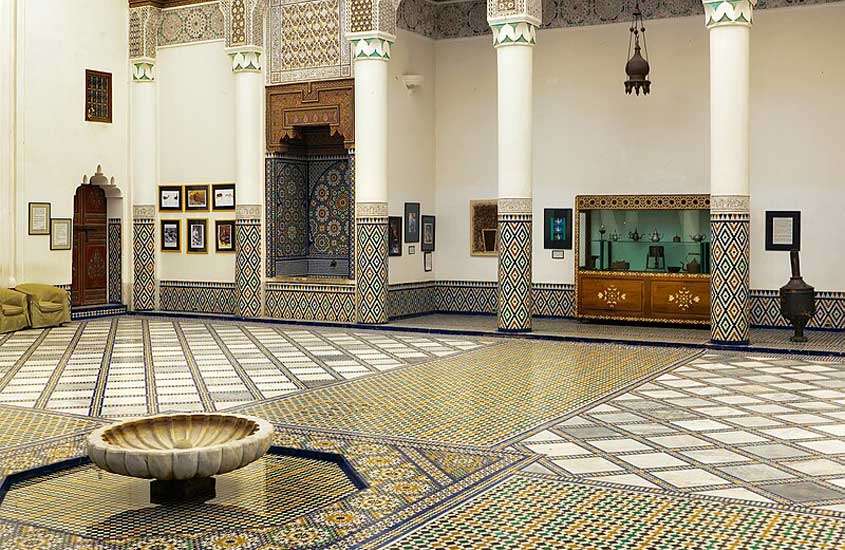 Pátio ornamentado tradicional de Marrocos com fonte, cristaleira, e peças decorativas
