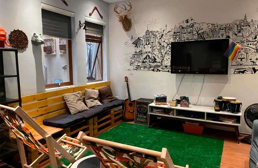 Sala de um dos melhores hostels em São Paulo com cadeiras, TV, sofá, volo, hack, janelas grandes e ventilador