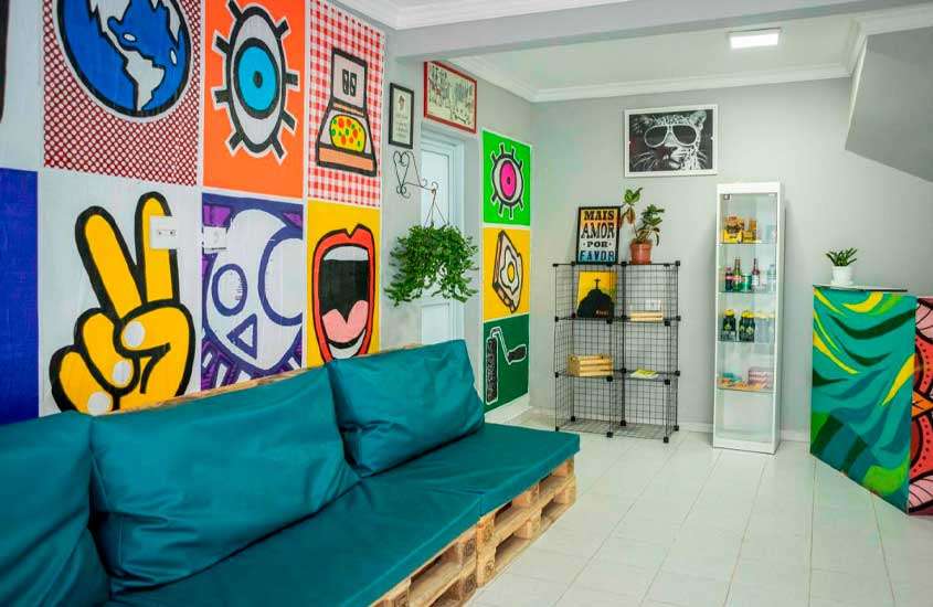 sala de hostel em são paulo com sofá, mural na parede, estantes e quadros