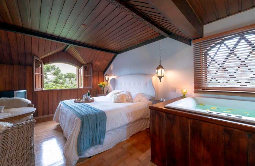 Quarto do melhor hotel no brasil para lua de mel com cama de casal, banheira, mesa, cadeiras, móveis de madeira, televisão e luminárias