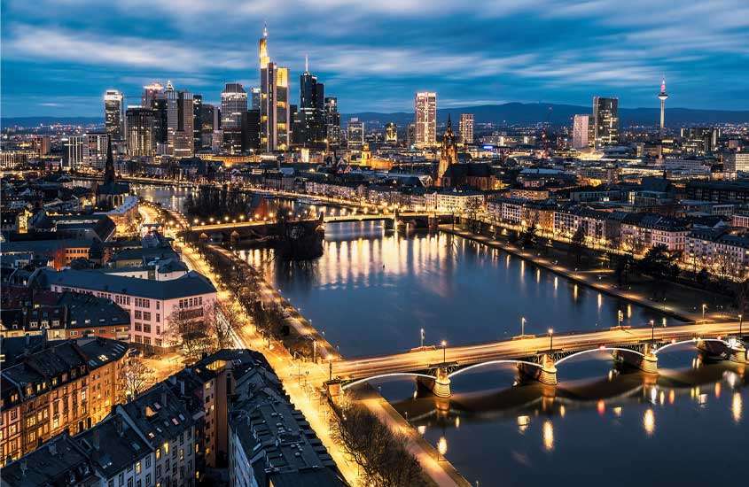Durante o anoitecer, vista panorâmica da cidade de Frankfurt Alemanha com prédios, casas, pontes, árvores e montanhas no fundo