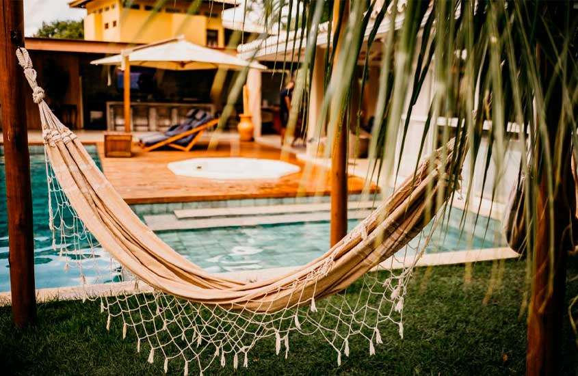 Em final de tarde, piscina, jacuzzi, rede e espreguiçadeiras em uma das casas de temporada na Costa do Sauípe