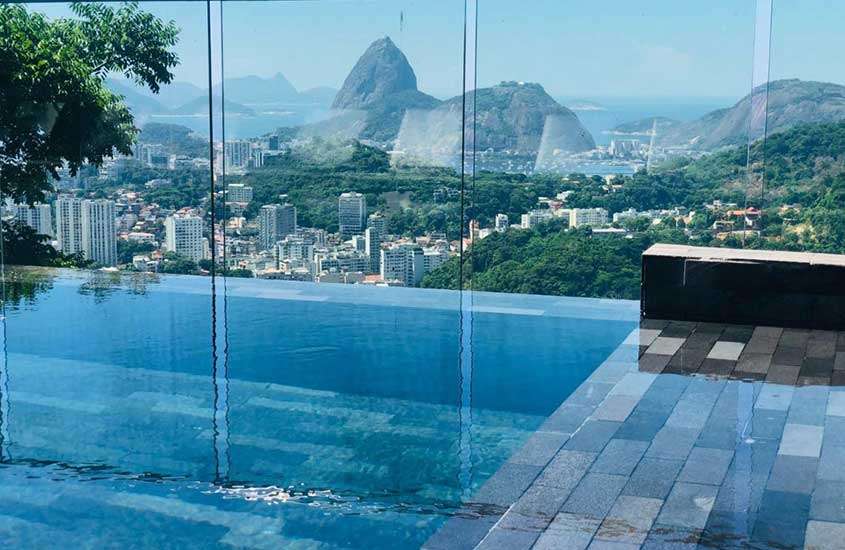 Durante o dia, piscina em área de lazer de hotel com vista para o mar e o Pão de Açúcar