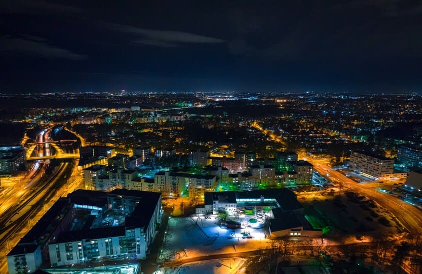 Vista aérea noturna de Helsinque com luzes da cidade iluminando o horizonte