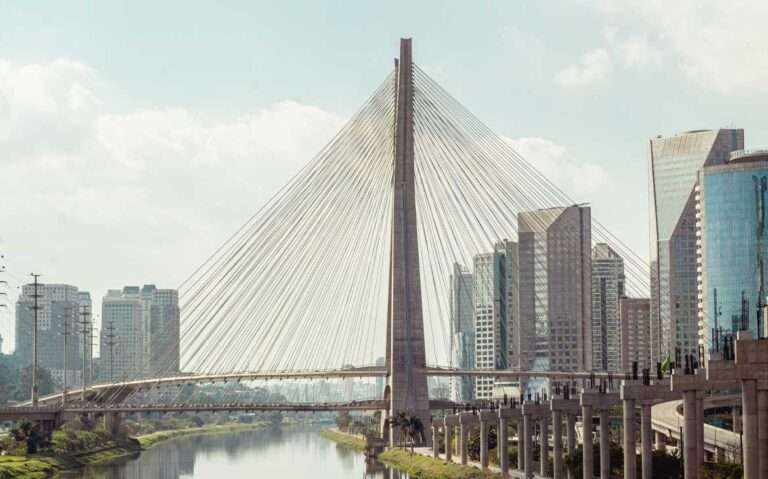 Em um dia de sol, ponte famosa em são paulo com rio no meio e prédios altos em volta