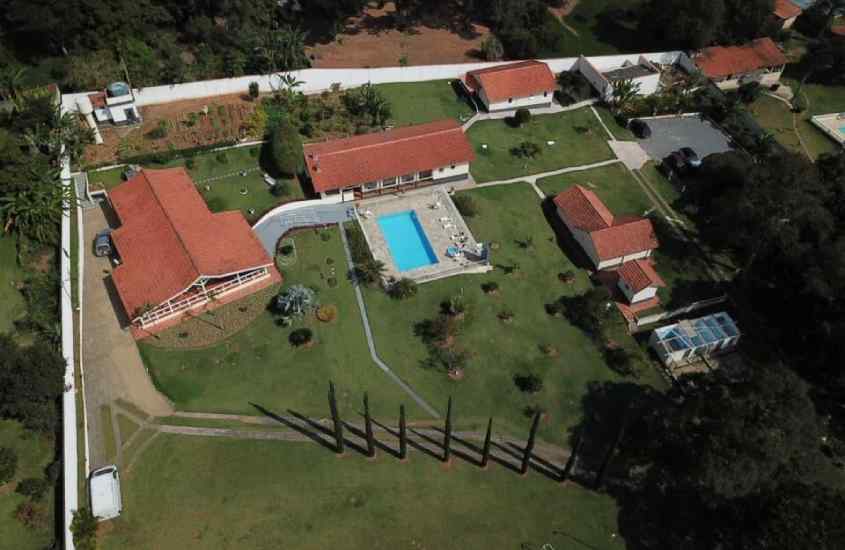 Vista aérea de um chalé com piscina, área gramada e várias árvores ao redor
