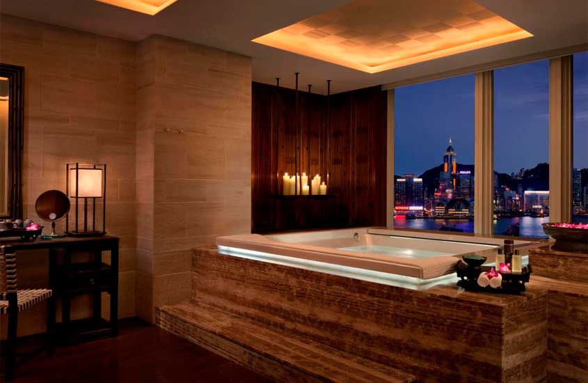 Banheiro de um hotel em Hong Kong com banheira, luminárias, velas, luminárias, flores e janela grande