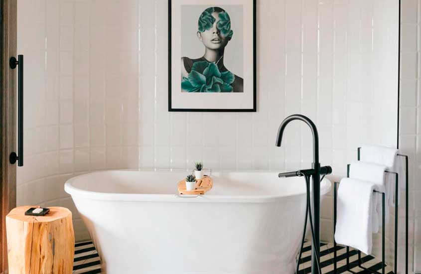 Banheiro de hotel onde se hospedar em vancouver com banheira, quadro decorativo, plantas ornamentais e toalhas