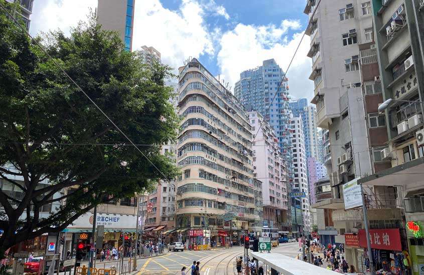 Em um dia de sol com nuvens, bairro em Hong Kong China com prédios, árvores e pessoas