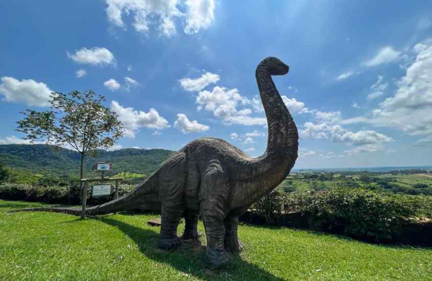 Em um dia ensolarado, dinossauro em área de lazer de um dos hotéis fazenda perto de ribeirão preto com vegetação ao redor