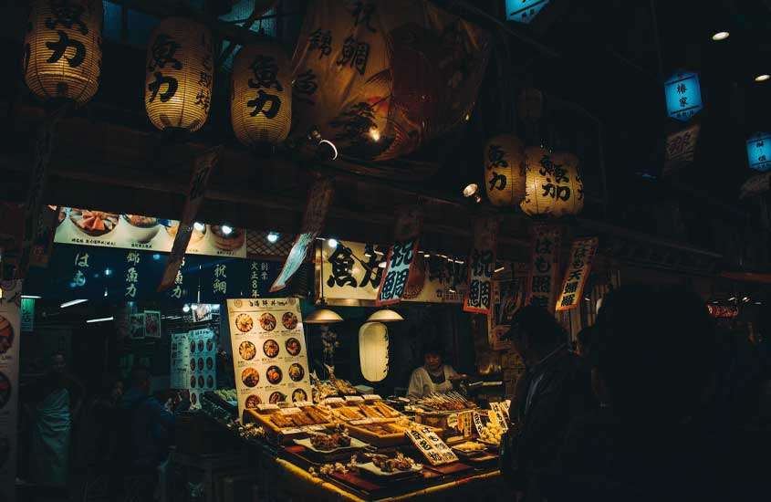 Durante a noite, mercado de comida da cidade de kyoto com pessoas olhando e luzes amarelas