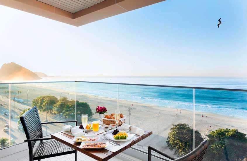 Em um dia de sol um dos hotéis em copacabana em frente ao mar com mesa de café da manha, cadeiras e litoral na frente