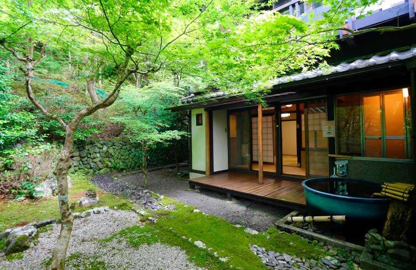 Em um dia nublado em kyoto japão banheira em varanda de hotel rodeado por árvores