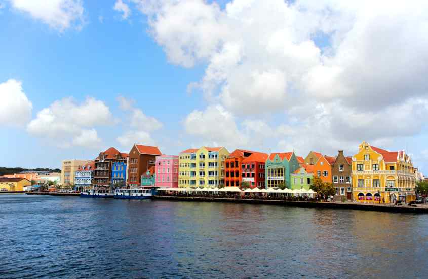 Durante um dia ensolarado, vista lateral da cidade com o mar na frente e casas coloridas