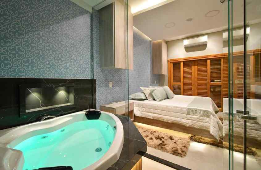Quarto de hotel com cama de casal, banheira de hidromassagem, armários de madeira, tapetes e ar-condicionado