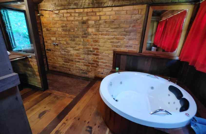 Banheiro de hotel em friburgo com banheira, espelho, janela acortinada e ducha