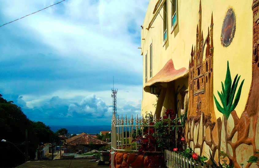 Em um dia nublado, lateral de uma das pousadas em São Thomé das Letras com decoração de castelo e cogumelos