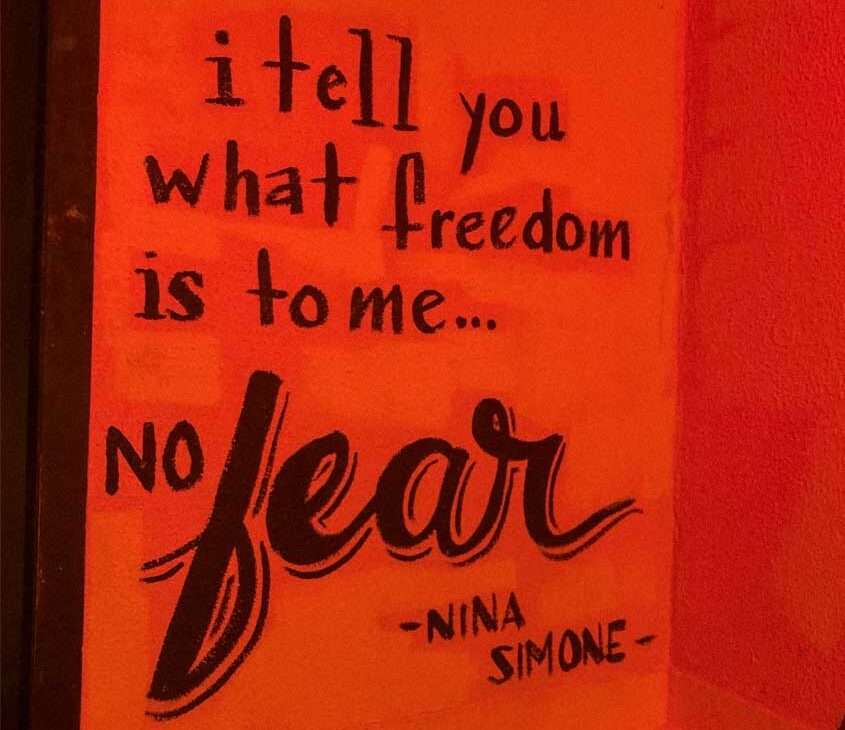 Parede laranja com a frase "i tell you what freedom is to me... no fear" - nina simone