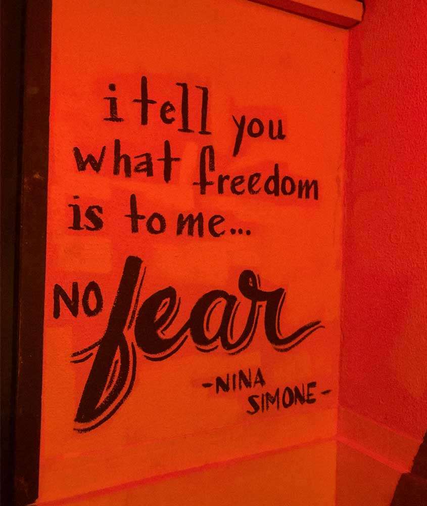 Parede laranja com a frase "i tell you what freedom is to me... no fear" - nina simone