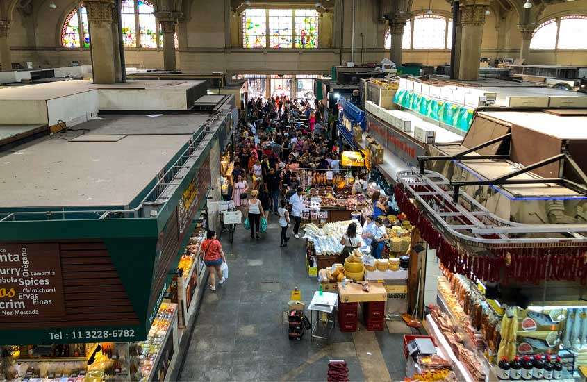 Interior de um mercado em são paulo com várias pessoas e lojas de comida