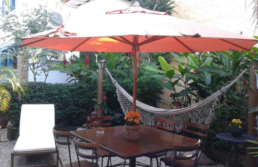 Em um dia de sol, área de descanso de um hotel no centro historico de paraty com mesas. cadeiras, espreguiçadeira, rede, guarda-sol e plantas decorativas