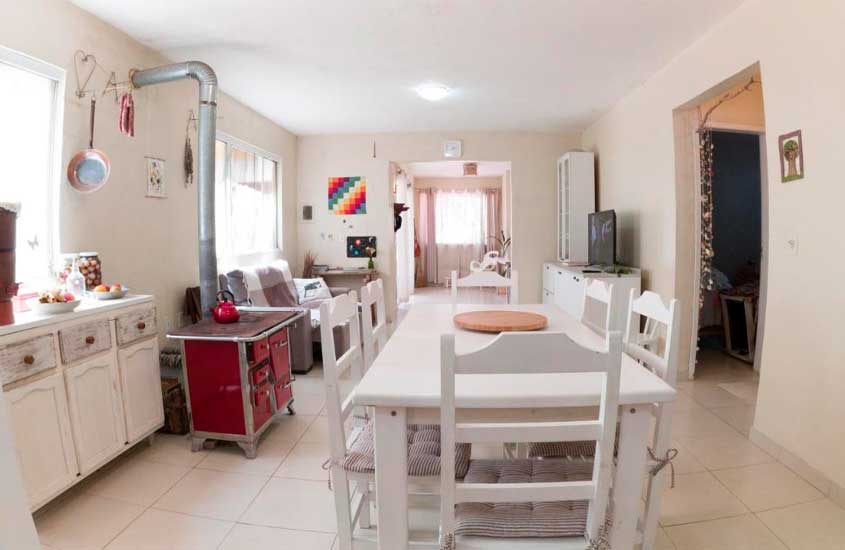 Interior de uma acomodação de pousada em balneário camboriú com sala de estar, mesa, cadeiras, cozinha e mini fogão a lenha