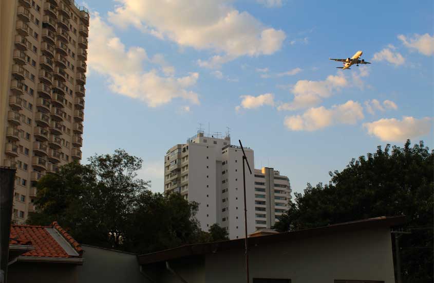 Em um final de tarde paisagem dos prédios com árvores e avião sobrevoando