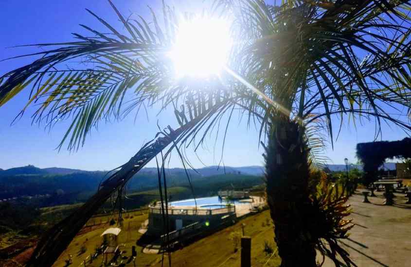 Durante um dia ensolarado, vista aérea de área de lazer de um hotel fazenda em serra negra sp com piscina, montanhas atrás e árvores