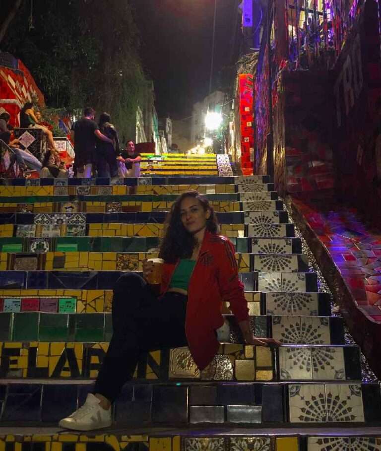 Durante a noite, escadaria famosa do Rio com pessoas sentadas, pessoas e luzes coloridas