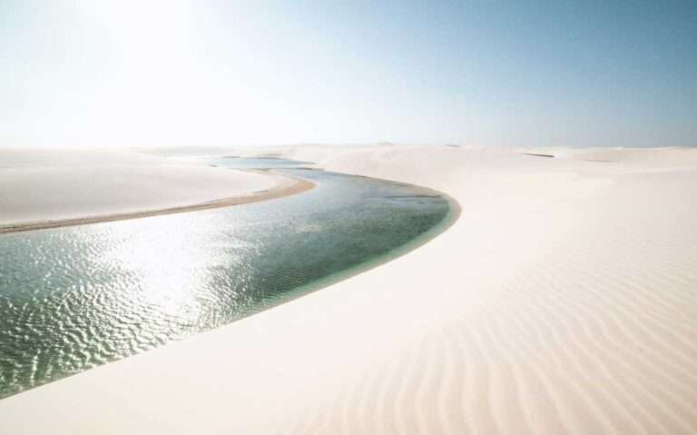 Durante uma manhã ensolarada, dunas dos Lençóis Maranhenses com lagoa no meio