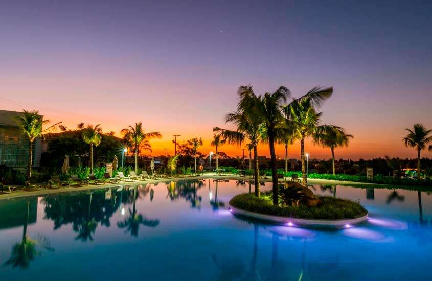 Durante o pôr do sol, área de lazer de um dos hotéis fazenda perto de campinas com piscina, espreguiçadeiras e árvores espalhadas ao redor