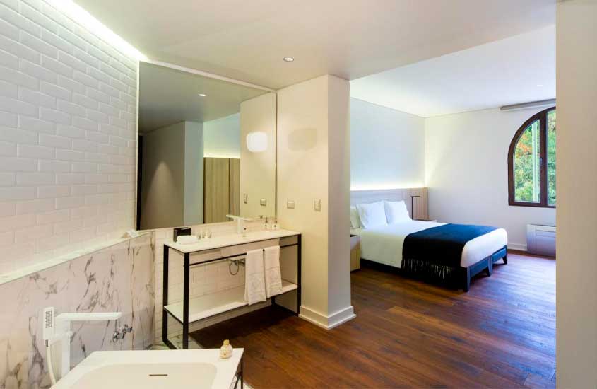 Quarto de um dos melhores hotéis em santiago do chile com cama de casal, banheiro integrado, espelho grande, janela e banheira