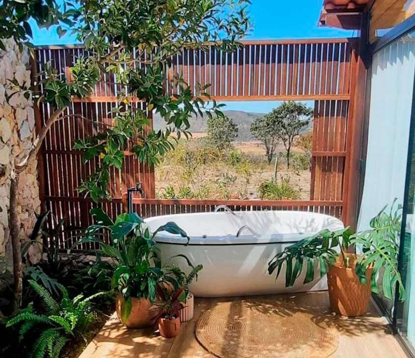 Em um dia de sol, área de banheira de um hotel fazenda perto de brasília com banheira, flores e árvores decorativas