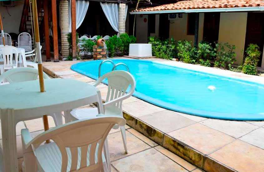 Em um dia de sol, área de lazer de um hotel nos lençóis maranhenses com piscina, mesas, cadeiras, plantas decorativas e cascata