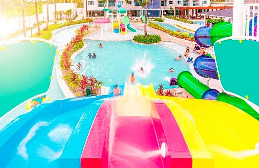 Durante uma manhã ensolarada, área de lazer de um resort para o carnaval com piscinas, brinquedos aquáticos, plantas e árvores decorativas