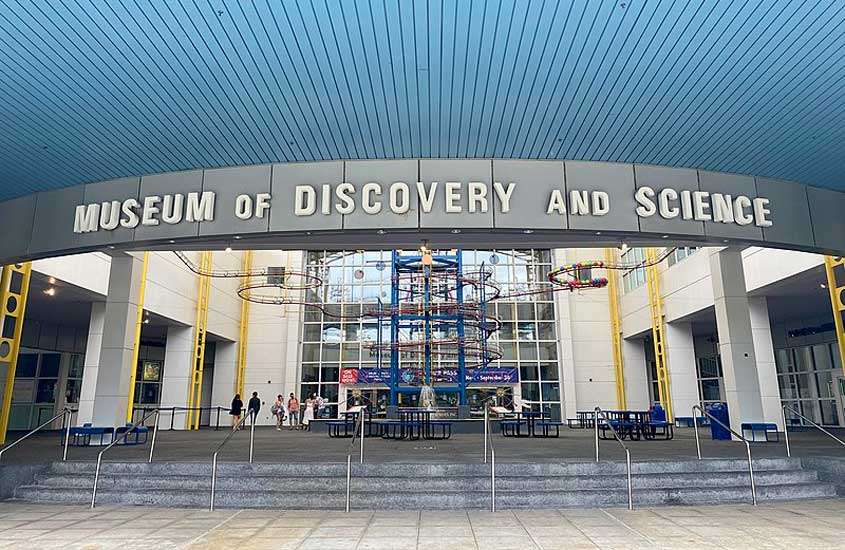 Fachada do museu do descobrimento e da ciência com bancos e pessoas
