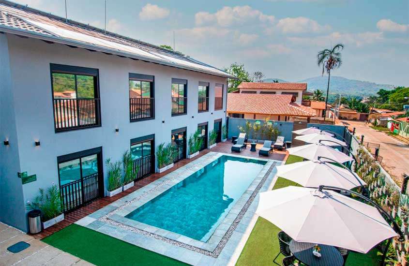 Em um dia da sol, área de lazer de um hotel para passar o feriado em Brasília com piscina grande, mesas, cadeiras, espreguiçadeiras e plantas ao redor