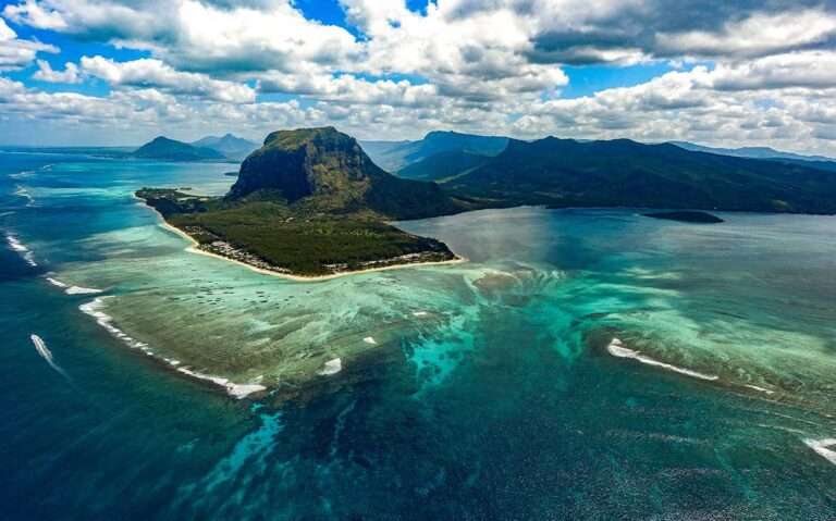 Em um dia de sol, vista aérea das ilhas maurício com montanhas ao redor e águas cristalinas