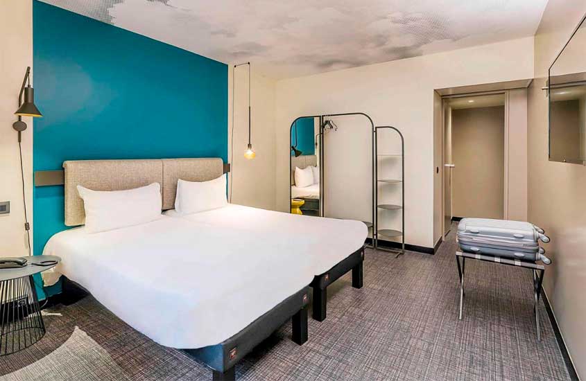 Quarto de hotel no centro de lisboa com cama de casal, espelhos, telefone, luminárias e banco com mala