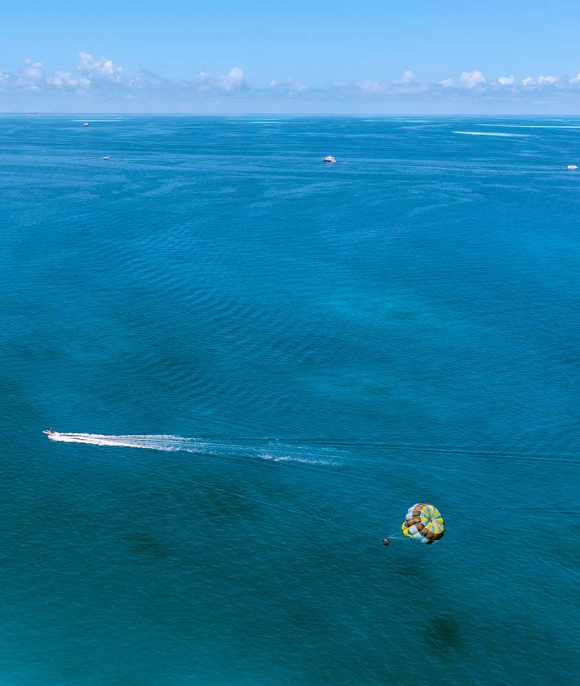 Vista aérea do mar das ilhas maurício com um barco levando atleta de kitesurf