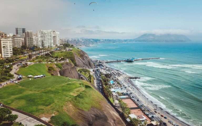 Durante um dia de sol, paisagem de Lima com praia de um lado e cidade do outro